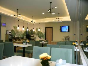 un restaurant avec des tables et des chaises et une télévision dans l'établissement GreenTree Inn Wuxi Quanshan Center, à Wuxi