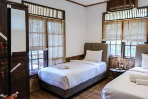 two beds in a room with windows at Menjangan Ecolodge - CHSE Certified in Banyuwedang