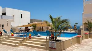 a pool with chairs and a palm tree next to a building at Fins Beach Guest House in Fins
