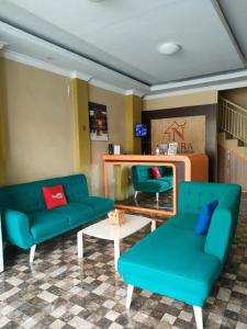 a living room with two blue couches and a table at Noura Guest House Syariah in Malang