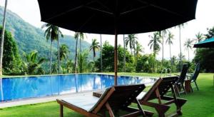 a swimming pool with two chairs and an umbrella at Brook Boutique in Madahapola