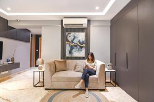 a woman sitting on a couch in a living room at FabHotel Prime The Water View Residency - Nr Bisarjan Ghat in Kolkata