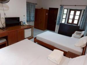 a room with two beds and a desk and a television at Chill Beach Resort in Pathiu