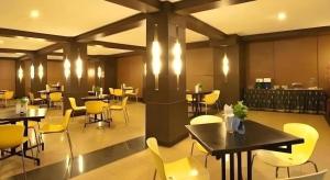 a restaurant with tables and chairs and yellow chairs at Hotel Bintang in Palur