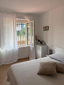 a white bedroom with a bed and a window at Magici Sogni-Bordighera in Bordighera