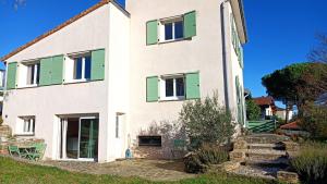 a white house with green shutters on it at Chambre d'hôte l'Olivier in Charly