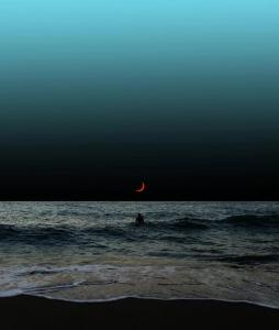 een persoon in de oceaan met de maan op de achtergrond bij Home holiday kozmai in Shëngjin