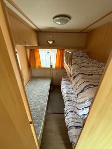 a small room with two beds and a window at Camping Noetselerberg - Sallandse Stee - Stacaravan 5pers in Nijverdal +11 photos