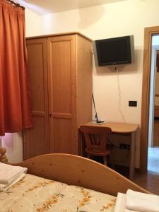a bedroom with a bed and a desk and a television at Albergo Al Cocul in Sùtrio