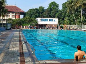 a man sitting in a swimming pool at Bumi Wiyata Hotel in Sugutamu Dua