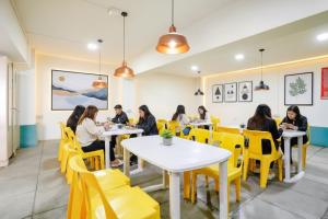 a group of people sitting at tables in a restaurant at FabHotel Happy Homely Stay - Airport road in Pune