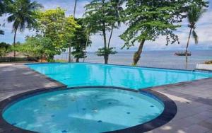une grande piscine bleue à côté de l'océan dans l'établissement Asana Biak Papua Hotel, à Fandoi