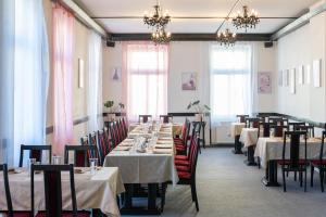 a dining room with tables and chairs and chandeliers at Hotel CB Royal in České Budějovice