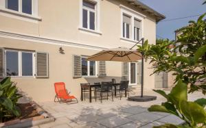 a patio with a table and chairs and an umbrella at Apartments Villa Adrienne in Mali Lošinj