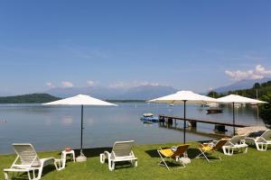a group of chairs and umbrellas on the grass near a dock at Il Giardino Sul Lago in Viverone