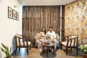 un homme et une femme assis sur un canapé dans un salon dans l'établissement Via Indian Residency, à Bangalore