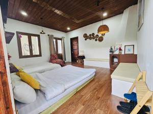 a large bedroom with a large white bed and wooden floors at NOMAD Home & Coffee in Da Lat
