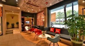 a lobby with a couch and chairs and a person sitting in a room at Ibis Xiamen Railway Station Hotel in Xiamen