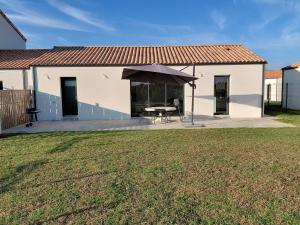 een huis met een tafel en een paraplu in een tuin bij Gîte du champ aisé in Montaigu-Vendée