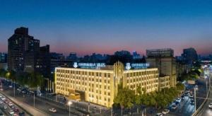 un grand bâtiment au milieu d'une ville à circulation dans l'établissement New Beacon Sunyee SPA Hotel, à Wuhan