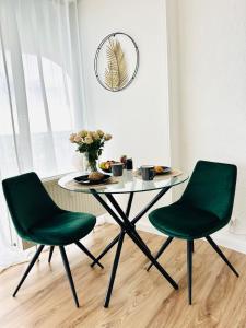 een tafel en twee groene stoelen in een kamer bij Charmantes Appartement im 25 OG mit Aussicht und 60 Zoll TV in Augsburg