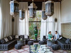 a man and woman sitting in a living room at Sofitel Marrakech Palais Impérial & Spa in Marrakech