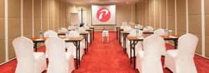 a conference room with tables and white chairs and a projector at d'primahotel Bandung in Bandung +149 photos
