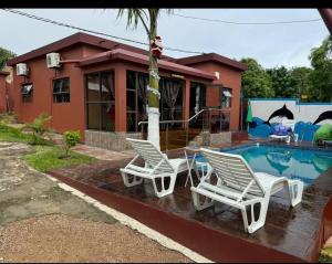 Vila Praia Do BileneにあるMagaia's Accomodationのスイミングプールの隣に白い椅子2脚 +4枚の写真