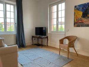 Una sala de estar con una silla y un televisor. en Maison Abbatucci, en Huningue