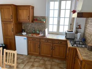 a kitchen with wooden cabinets and a white refrigerator at Maison Abbatucci in Huningue