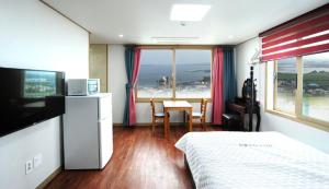 a bedroom with a bed and a table with a view of the ocean at Seongsanpo love Pension in Seogwipo