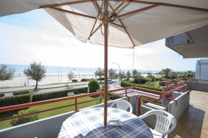 een tafel en stoelen op een balkon met een parasol bij Vistamare in Martinsicuro