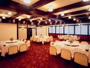 une salle de banquet avec des tables et des chaises blanches dans l'établissement HotelNewYama, à Nagano