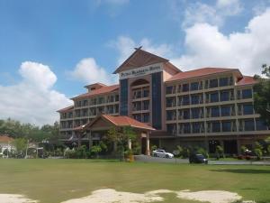 a hotel building with a green lawn in front of it at Putra Brasmana Hotel in Kuala Perlis