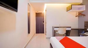 a bedroom with a bed and a desk with a chair at GM Holiday Hotel Permai Jaya in Kampong Tebing Rabak