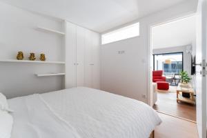 a white bedroom with a bed and a red chair at Gaia Bella Guest House in Vila Nova de Gaia