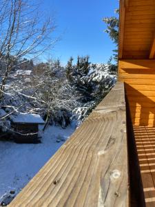 a wooden deck with snow on the ground at Chalet authentique au calme, en lisière de forêt, montagne, sentiers 15mn Gérardmer & Alsace "Chalet Mon beau sapin" in Anould