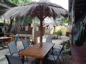 Una mesa y sillas de madera bajo una sombrilla de paja en Hostel Finisterre, en La Pedrera