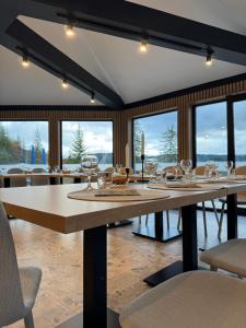 a dining room with a large table with chairs and windows at Barka in Borsec