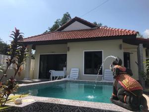 a house with a swimming pool with a statue in front of it at Villa Mokara Brassia 2 bedrooms by orchids pool villas in Ko Lanta