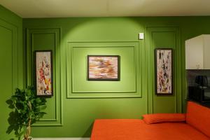 ラホールにあるPenta Square Superior Executive Apartments-DHA Lahoreの壁に3枚の絵が飾られたグリーンルーム +5枚の写真