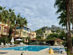 a swimming pool with chairs and palm trees and buildings at Villa Konakli in Konaklı