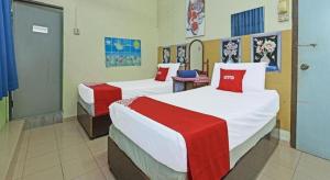 a bedroom with two beds with red and white sheets at SPOT ON 90625 Super Green Grass Hotel in Yong Peng