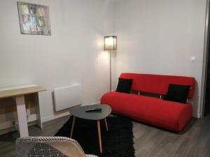 ein Wohnzimmer mit einem roten Sofa und einem Tisch in der Unterkunft Plénitude guillot in Le Mans