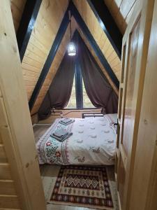 a small bed in a room with a window at Cabana Sofia in Burzeşti