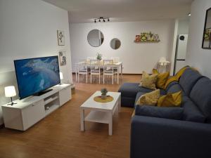 a living room with a blue couch and a tv at Apartamento la Última Orilla - Mar y Garaje in Malpica