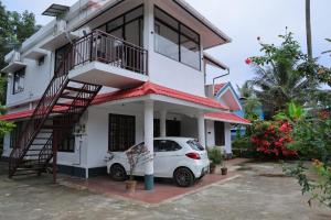 WayanadにあるJosebas Inn Vythiriの前に車が駐車されている白い家
