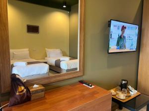 una camera d'albergo con due letti e uno specchio di Work Den Chiangrai a Chiang Rai