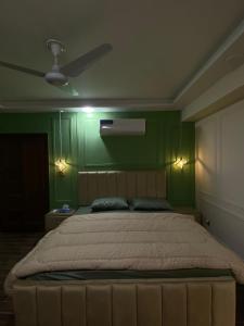 a bedroom with a large bed with green walls at Luxury, Modern & Central Apartment Islamabad, with Gym, Near Motorway & Airport in Islamabad