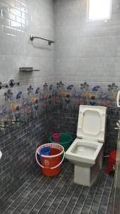 a bathroom with a toilet and flowers on the wall at Rainbow Guest House in Mahabalipuram